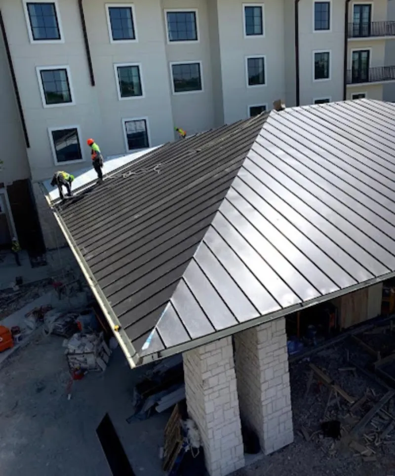 Crew installing standing seam metal roof panels on a commercial project in Schriever